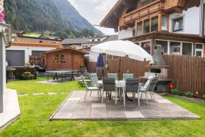 a patio with a table and chairs and an umbrella at Gästeheim Krößbach in Neustift im Stubaital