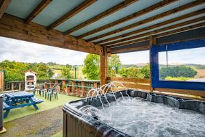 a hot tub on a patio with a large window at Welsh Row House in Llandegla