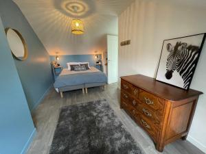 um quarto com uma cama e uma cómoda com uma imagem de zebra em Maison de campagne entièrement climatisée avec grand jardin em Pressagny l'Orgueilleux