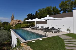 uma piscina com cadeiras e guarda-sóis num quintal em Monte Alta em Salon-de-Provence