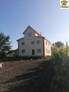 a large white house on the side of a field at Khutorok Svergio in Chesnivka