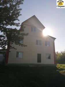 Una gran casa blanca con el sol detrás. en Khutorok Svergio, en Chesnovka