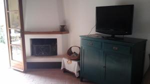 a living room with a television on a dresser with a fireplace at Appartamento con vista panoramica in Pienza