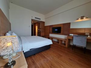 een grote hotelkamer met een bed en een bureau bij Swan Garden Hotel in Melaka
