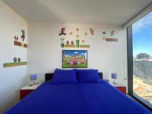 a bedroom with a blue bed and a window at Nintendo Theme-Adelaide CBD-King Bed-Spa-Gym-BBQ in Adelaide