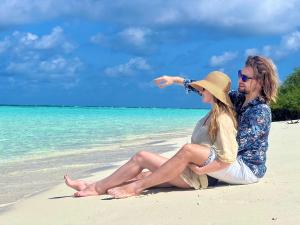 un hombre y una mujer sentados en una playa en Ocean Beach Inn - Maldives, en Hangnaameedhoo