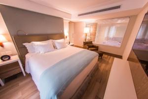 a hotel room with a large bed and a window at Vogal Luxury Beach Hotel & SPA in Natal