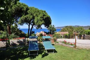 un jardín con 2 sillas azules y flores en Casa del Mare - Oasi verde a soli 100m dal mare!, en Marciana Marina