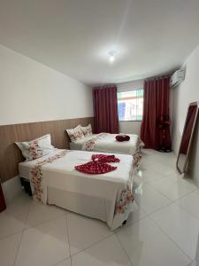 2 camas en una habitación con cortinas rojas en Hospedagem Central I, en Arraial do Cabo