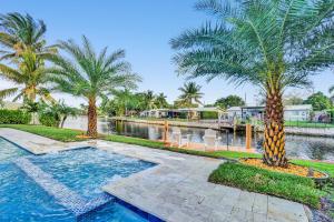 a house with a swimming pool with palm trees at New! Waterfront Heated Pool & Jacuzzi 2 mi to Beach - Fishing Pier Relaxing SPA & Hammock in Fort Lauderdale