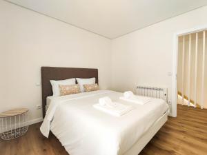 a white bedroom with a large bed with two towels on it at Senhora dos Mares - Apartment in Ribeira in Viana do Castelo