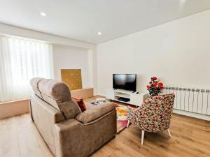 a living room with a couch and a chair and a television at Senhora dos Mares - Apartment in Ribeira in Viana do Castelo