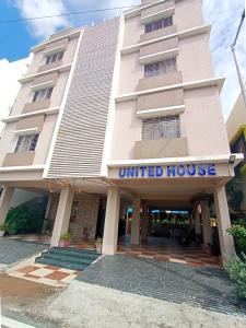 a white building with a united house sign on it at Hotel United House in Shirdi