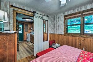 a bedroom with a red bed and a kitchen at Cozy Ennice Cabin on the Blue Ridge Parkway! in Glade Valley