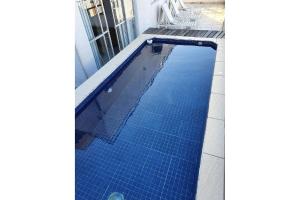 a swimming pool with blue tiles in a house at Cobertura Piscina Enseada Guaruja in Guarujá