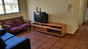 a living room with a tv and a couch at Apartamentos Enseada Guaruja in Guarujá