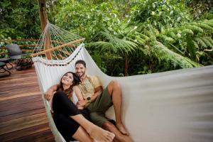 a man and a woman sitting in a hammock at Ecolirios Boutique Hotel and Spa in Guácimo