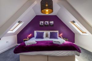 a purple bedroom with a bed in a attic at 4 bed home sleeps 8 & Close to the QMC hospital in Nottingham