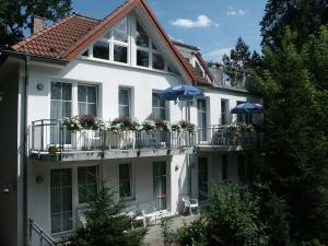 ein großes weißes Gebäude mit Balkonen und Sonnenschirmen in der Unterkunft Waldhaus Mühlenbeck bei Berlin in Mühlenbeck