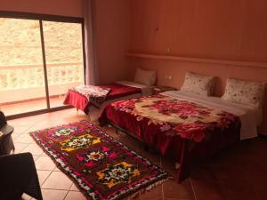 1 dormitorio con 2 camas, ventana y 2 alfombras en Hotel taborihte en Tinerhir