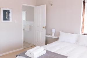 a white bedroom with a bed with towels on it at Nahoon Beach Villas Self Catering Apartments in East London