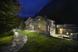 une vieille maison en pierre sur une cour herbeuse la nuit dans l'établissement Casa Alpina San Luigi, à Campodolcino