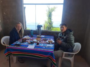 a man and woman sitting at a table with food at Titicaca Perka Lodge in Puno
