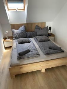 a large bed with grey pillows on top of it at Fenyves Beach Apartman in Balatonfenyves