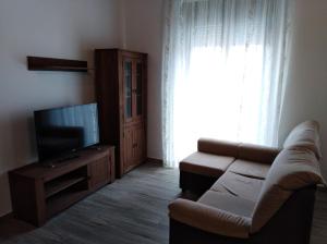 sala de estar con sofá y TV de pantalla plana en Apartamentos turísticos Cambil, en Cambil