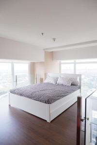 - une chambre blanche avec un grand lit dans une pièce dotée de fenêtres dans l'établissement Time suite- Bizloft Karawaci, à Klapadua