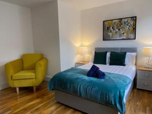 - une chambre avec un lit et une chaise jaune dans l'établissement De Parys Serviced Flat in Bedford 4, à Bedford