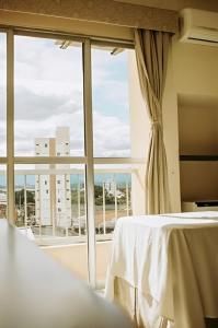 een slaapkamer met een bed en een groot raam bij Olympia Hotel in Lorena