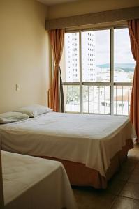 two beds in a room with a large window at Olympia Hotel in Lorena