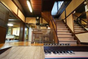 a man standing in the middle of a room with stairs at Hostel Murasaki Ryokan in Takayama