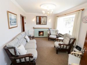 sala de estar con sofá, sillas y chimenea en Sea Watch House, en Roundstone