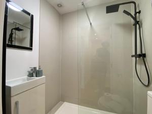 een witte badkamer met een douche en een wastafel bij De Parys Penthouse 5 in Bedford in Bedford