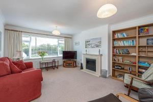 uma sala de estar com um sofá vermelho e uma lareira em Lon Penrhyn em Benllech