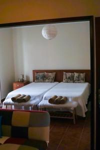 1 dormitorio con 2 camas y espejo en Casa das Hortênsias, en Ponta Delgada