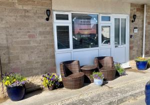 un groupe de chaises en osier devant une porte dans l'établissement Apartment 49, Ground floor, 2 Bedrooms with parking, à Brean