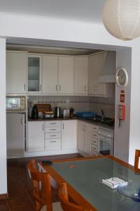 cocina con armarios blancos y mesa de cristal en Casa das Hortênsias, en Ponta Delgada