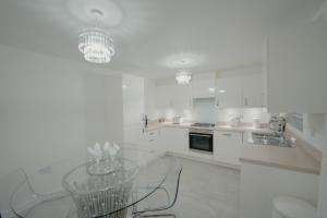 a white kitchen with a glass table in it at Willow Heights Modern 5-7 Persons/3 Bed Detached in Rotherham