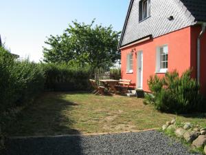 a red house with a picnic table in the yard at Rosmarinchen in Waabs