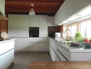 una cucina con armadi bianchi e lavandino di Das Grasberghaus a Grasberg