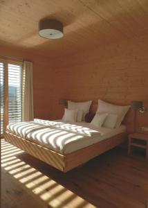 una camera da letto con un letto grande con lenzuola e cuscini bianchi di Das Grasberghaus a Grasberg