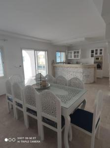 ein Esszimmer mit einem weißen Tisch und Stühlen in der Unterkunft Villa La Palmeraie d'Arkou, grande piscine in Arkou