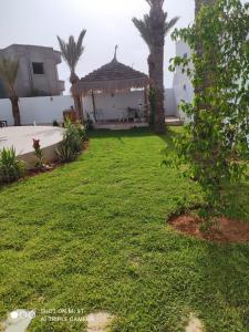 un patio trasero con cenador y césped en Villa La Palmeraie d'Arkou, grande piscine en Arkou