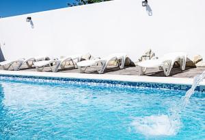 a swimming pool with white chairs and a fountain at Villa Castillo de Alba in Barbate