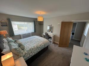 a bedroom with a bed and a desk and a window at Two bedroom house with enclosed gardens and 2 car drive in Caeʼr-geiliog