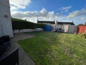 a backyard with a yard with a fence and a house at Two bedroom house with enclosed gardens and 2 car drive in Caeʼr-geiliog