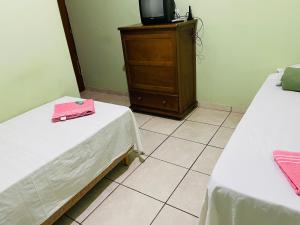 a room with two beds and a tv on a dresser at Hotel Solaris in Três Lagoas